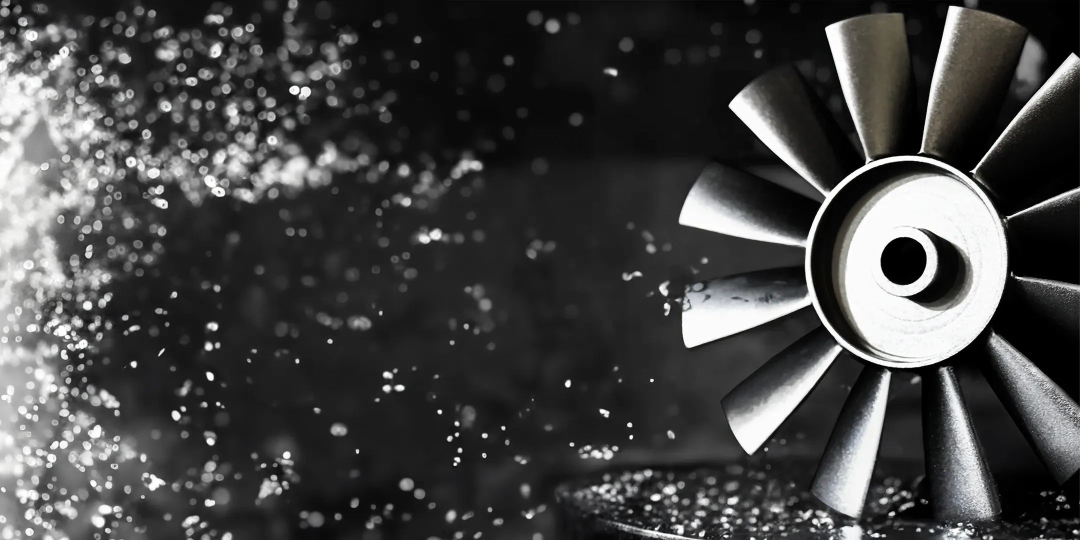 Close-up of a brushless cooling fan’s rotor blades on the right, with water droplets and metal shavings spraying across a dark, textured background.